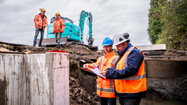Vier medewerkers staan buiten op een bouwplaats