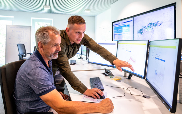 Twee medewerkers bekijken op kantoor meerdere beeldschermen